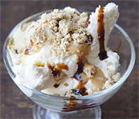 an image of a bowl of Labneh Ice Cream, a thick, creamy, and tangy yogurt cheese (usually made from goat's milk) from the Middle East and topped with tahina (ground sesame), silan (date syrup), honey, and sesame seeds